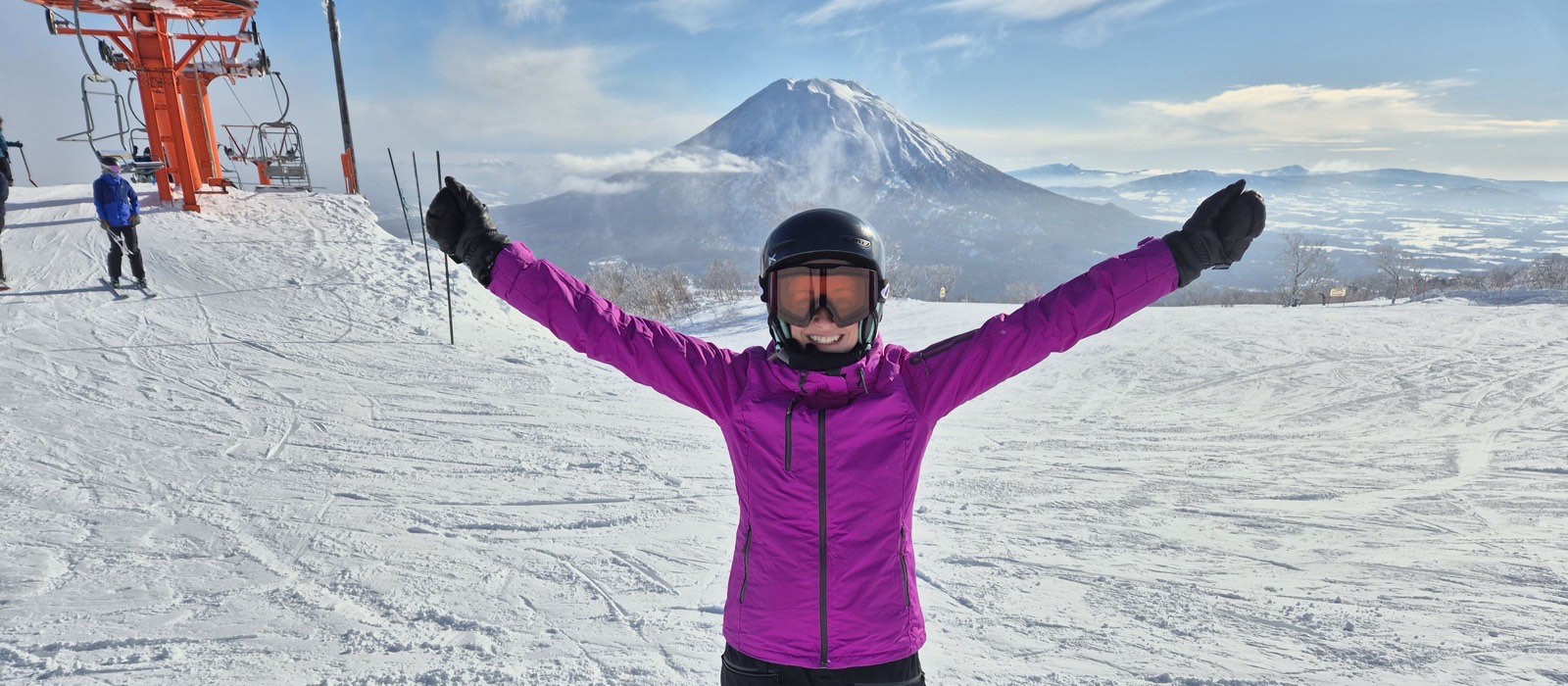 Ramat Niseko, Hirafu, Niseko — Snowboarder celebrating on a bluebird day at Niseko Hirafu with Mt Yotei behind