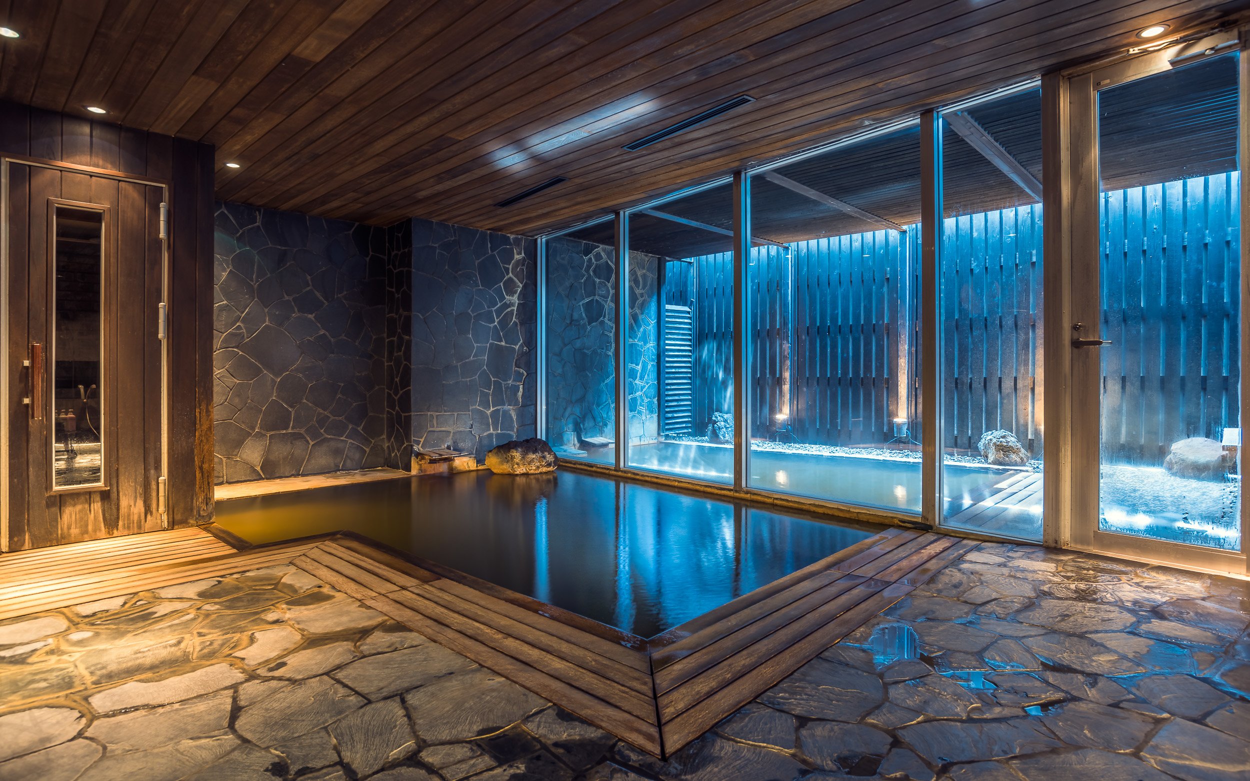 An indoor-outdoor onsen bath at a Niseko property, steam rising against snow
