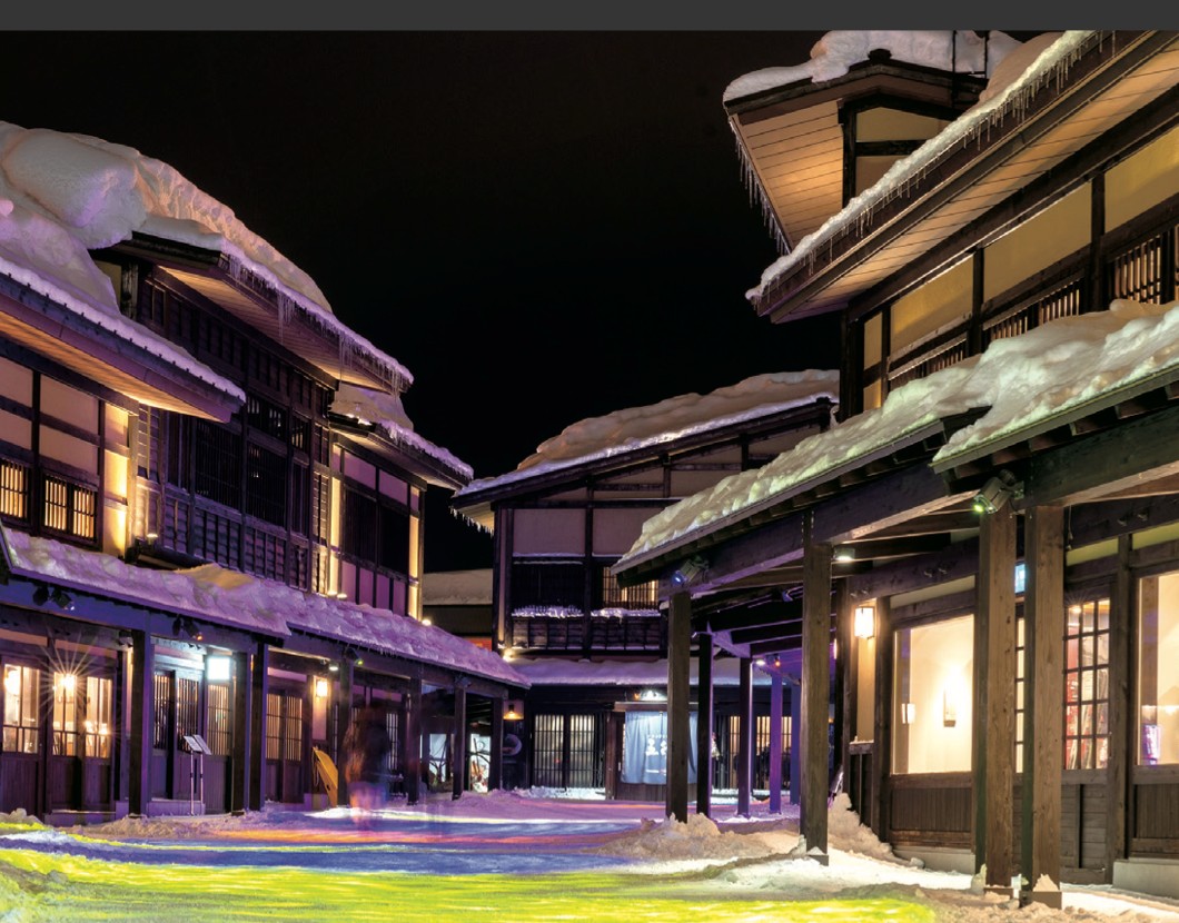 Niseko-Yo at night, snow-covered timber buildings lit with projection artwork, Niseko Village